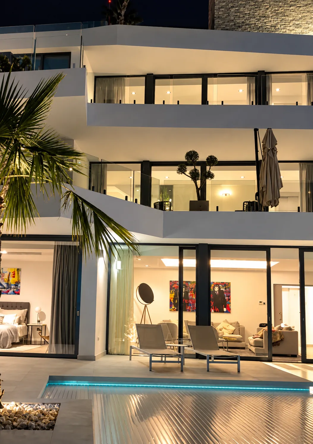 Villa med upplysta glaspartier och pool en kväll