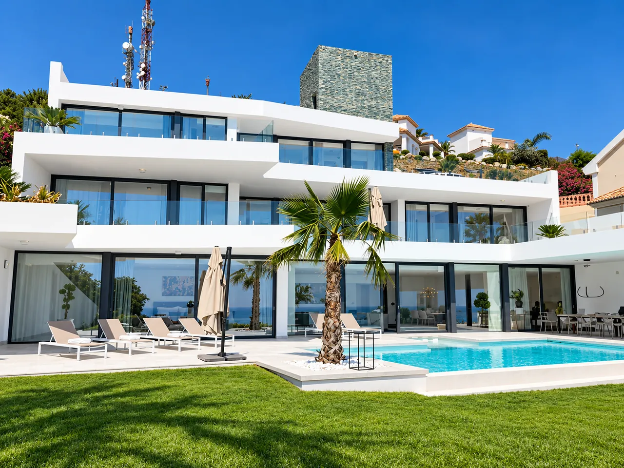 Vit villa i flera plan med pool och palmer